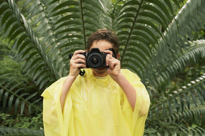 $1 solutions - Young boy in raincoat taking photos in forest during field trip