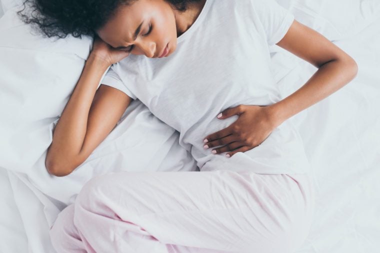 Woman in bed suffering from stomach ache