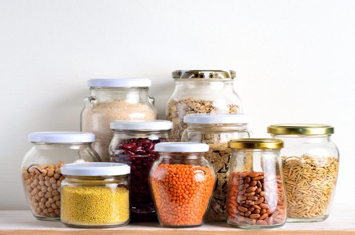 Collection of cereals in storage jars in pantry.
