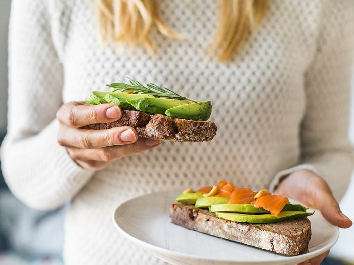 Natural remedies for high blood pressure - close up of woman holding plate with avocado toast as fresh snack, day light.