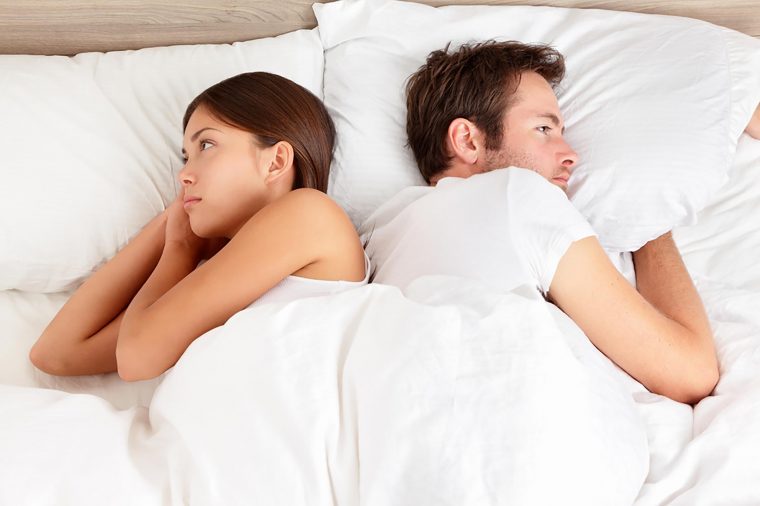 Couple facing away from each other in bed