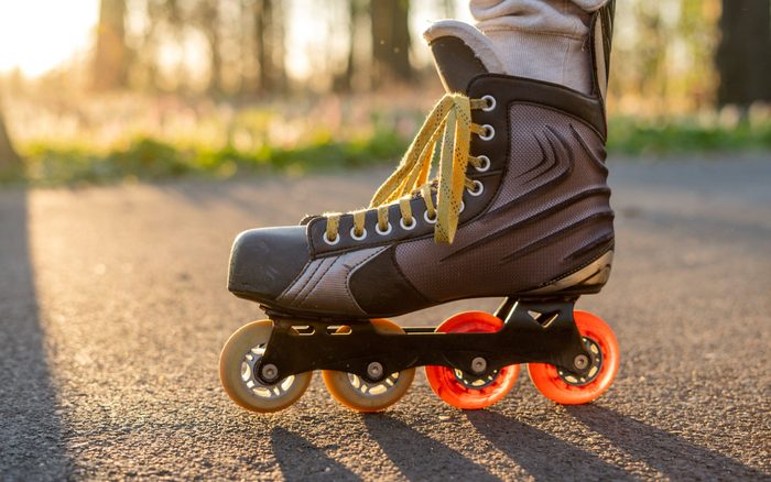 Close view of inline skates. Outdoor inline skating on smooth concrete ground. Ice skating at sunset. Background with bokeh