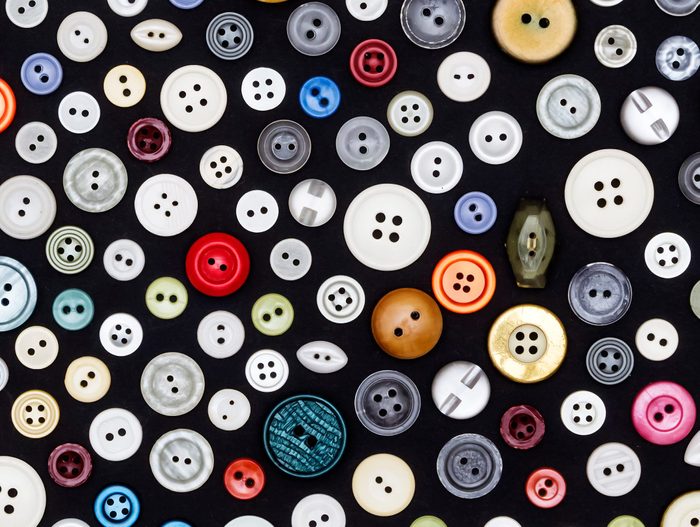 $1 solutions - buttons of different colors and sizes are randomly scattered on a dark surface
