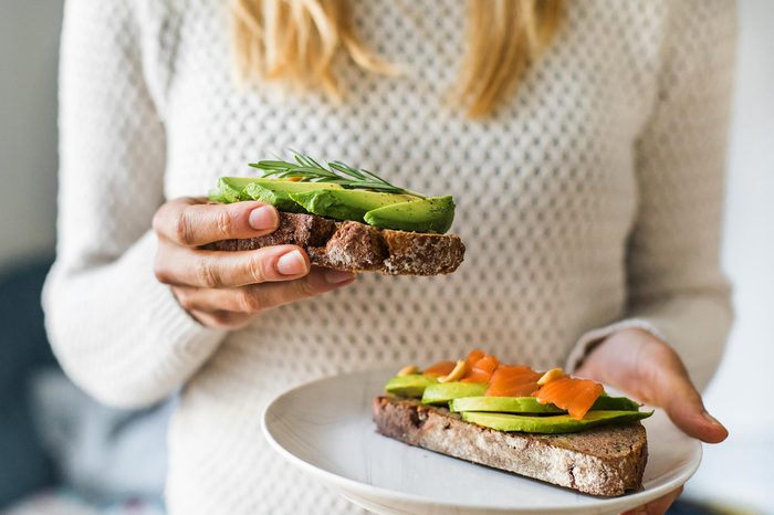 close up of woman holding plate with avocado toast as fresh snack, day light.