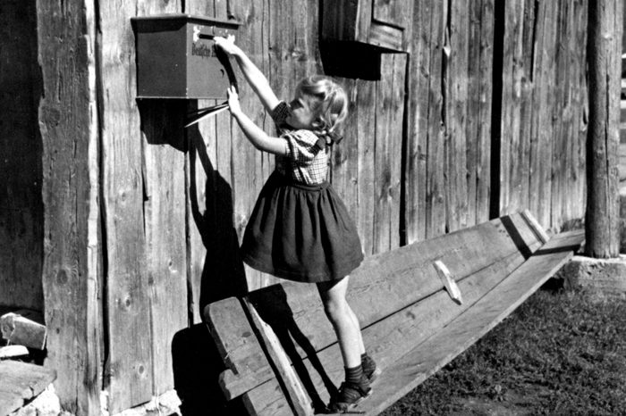 little girl reaching for mailbox