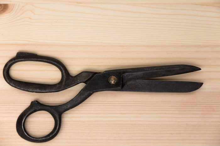 old tailor's scissors on a light wooden table