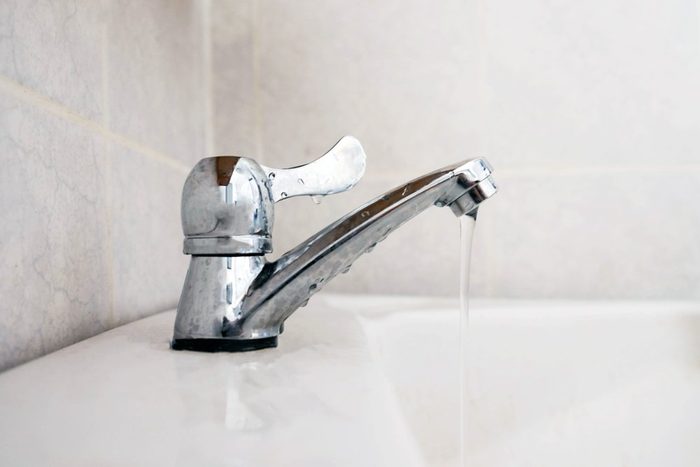 Close up dripping water drop of faucet in the bathroom , save water concept