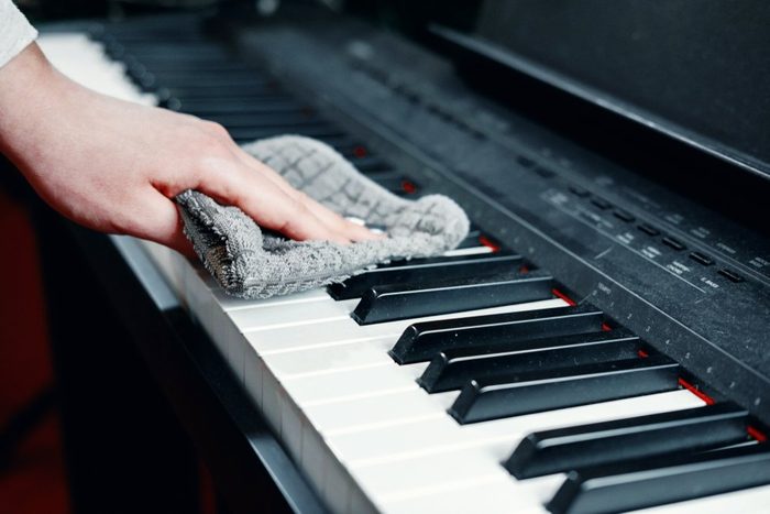 dirty piano, wipe dust from a piano, a woman's hand with a rag for cleaning