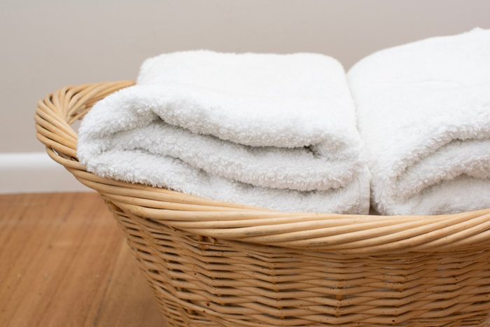 Soft white towels folded place in the rattan basket place on the wooden floor