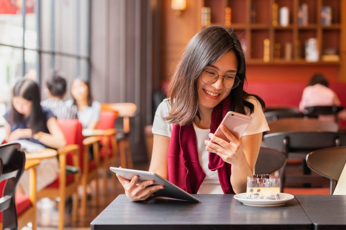Lifestyle, Technology Concept - Asian woman using app on a smart phone while relaxing in cafe during free time with copy space. 