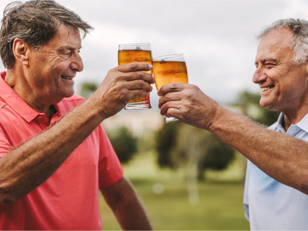 Two men holding beers on golf course