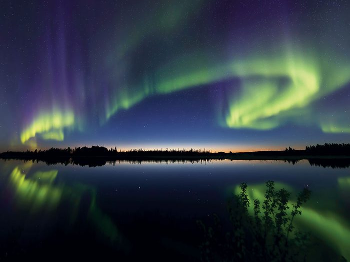 Northern lights pictures - green aurora reflected on lake