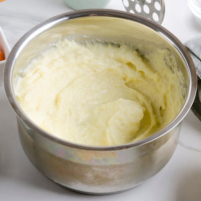 Delicious fresh cooked mashed potatoes in the pot, vegetables and spices on the white table; Shutterstock ID 1411764926; Job (TFH, TOH, RD, BNB, CWM, CM): TOH