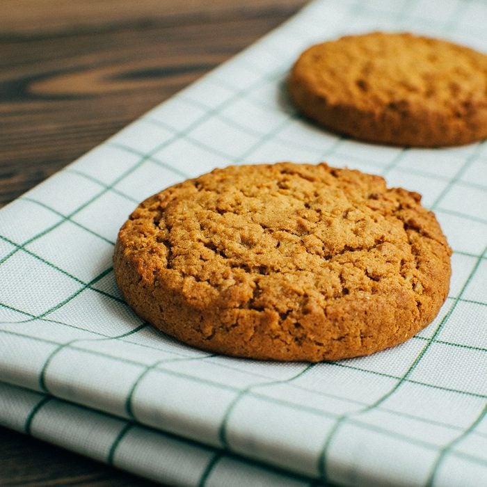 genius holiday tips - Close-up three tasty oatmeal cookies laying at the green checkered textile kitchen towel at wooden surface of bakery, cafe or kitchen table in the morning during the breakfest in cozy atmosphere