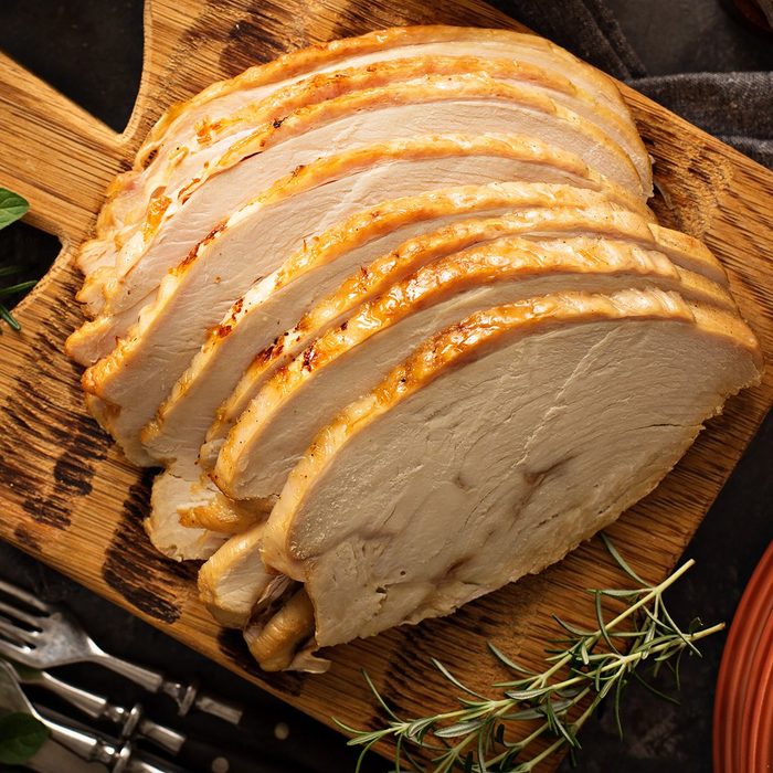 Sliced roasted tukey breast for Thanksgiving or Christmas dinner with side dishes overhead shot; Shutterstock ID 735091306