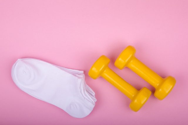 yellow dumbbells and white socks on a pink background