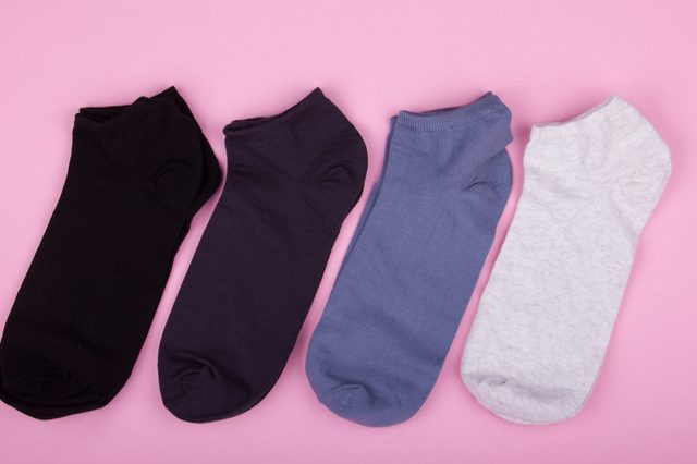 four pairs of different colored socks on a pink background