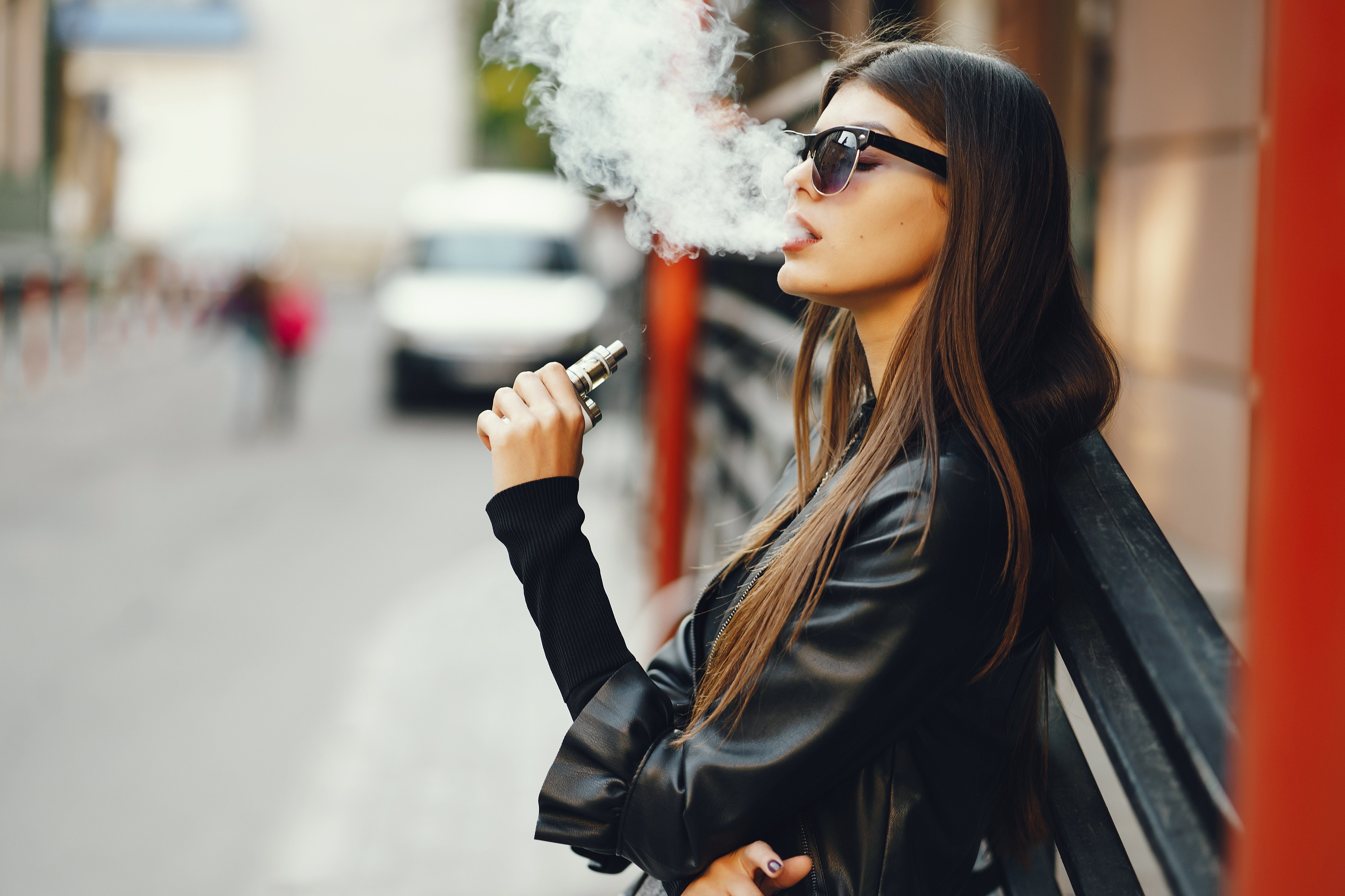 stylish girl smoking an e-cigarette as she is walking through the city