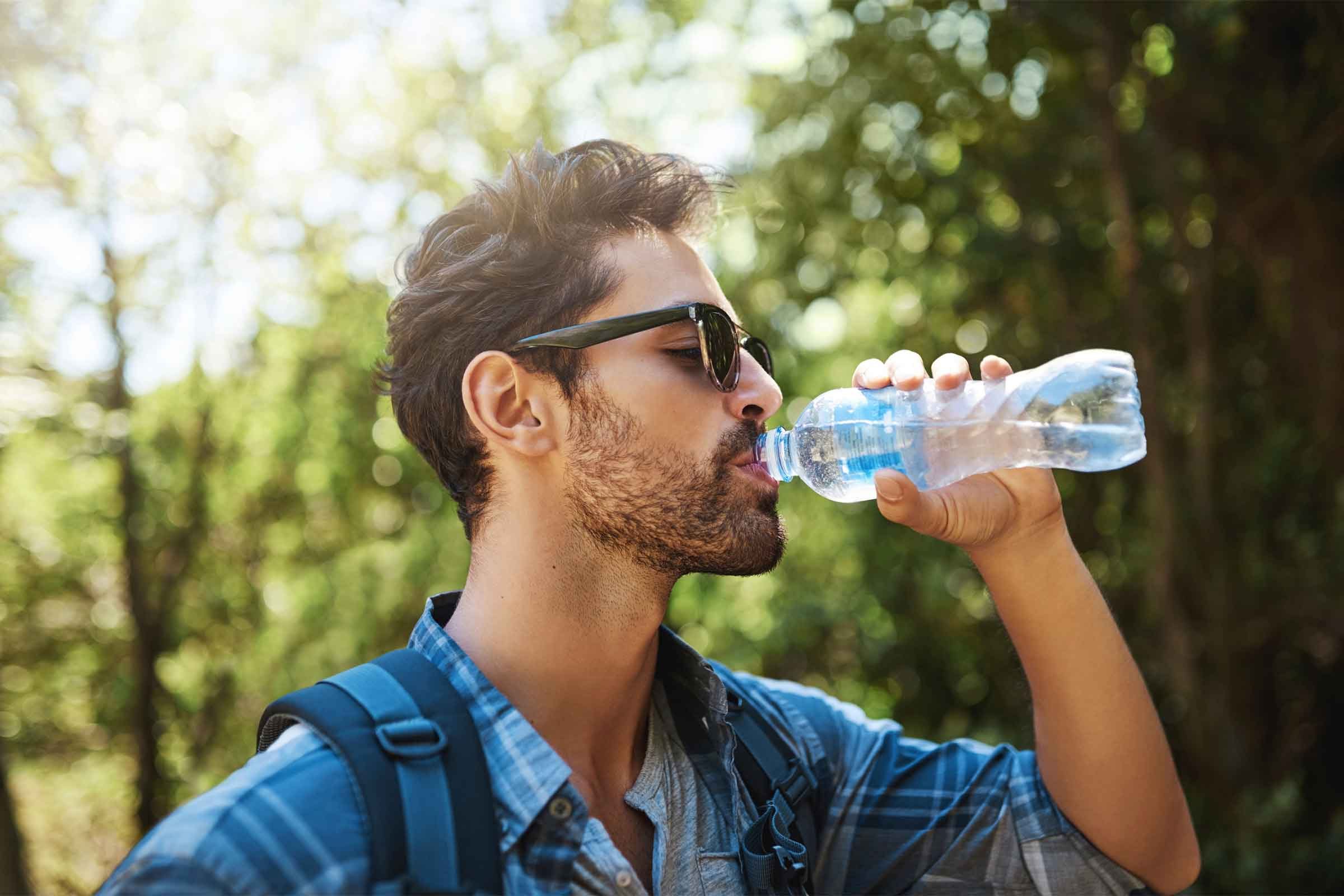 Handsome bearded man drinking from water bottle