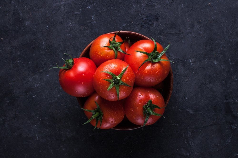 Red, ripe tomatoes on a dark background. Harvesting tomatoes. Top view