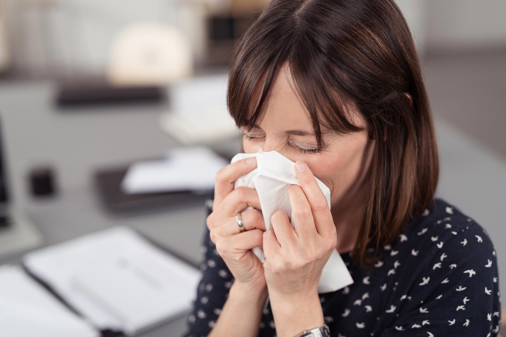 Woman blowing nose into tissue