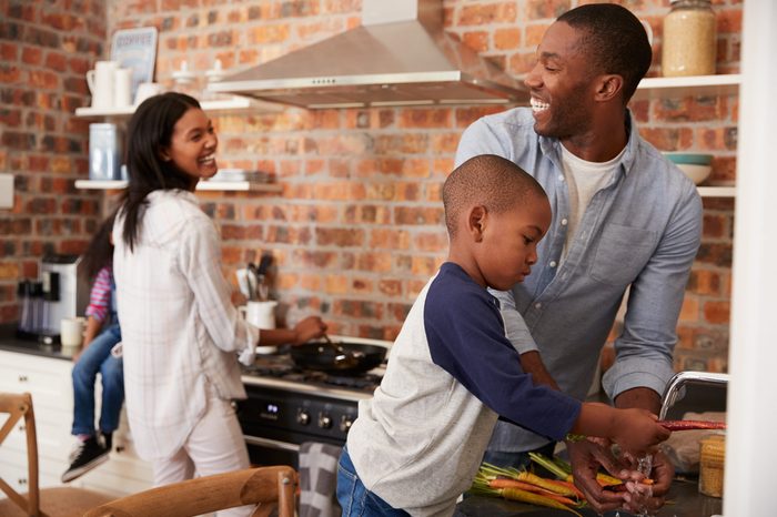 Children Helping Parents To Prepare Meal In Kitchen