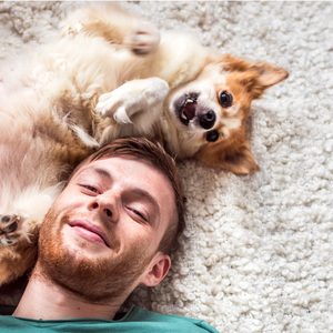 How to be happy - Young smiling man playing with his pet dog