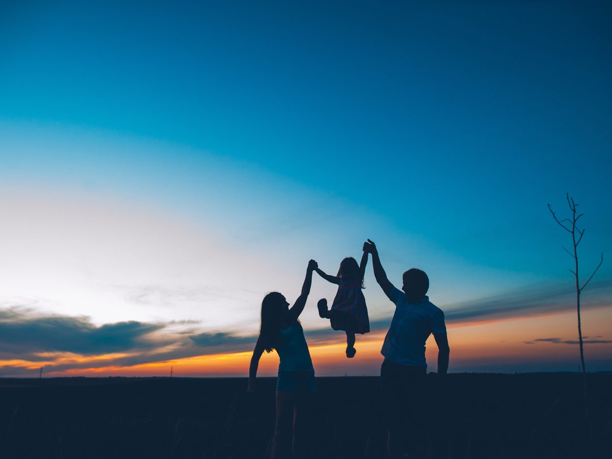 Silhouette of parents lifting up child