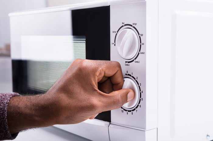 Close-up Of A Man's Hand Adjusting Temperature Of Microwave Oven