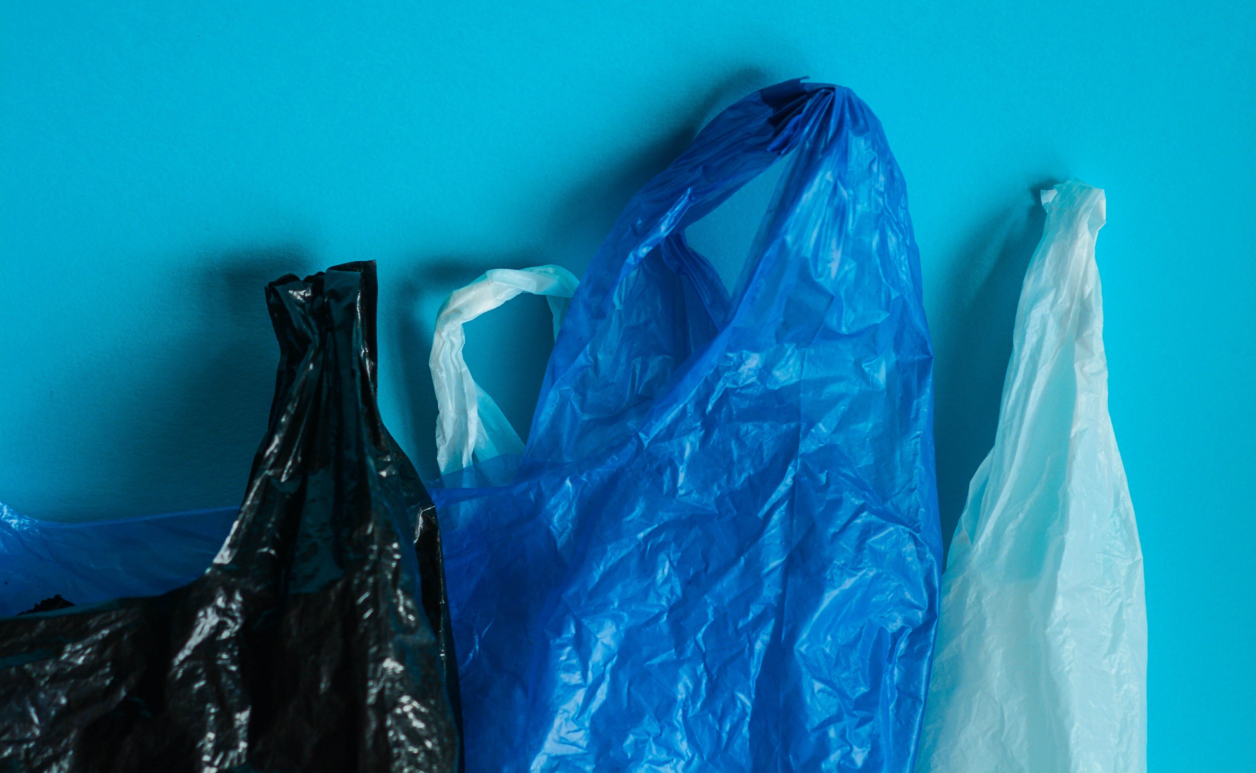Black, blue and white plastic bags on blue background. Representation of plastic pollution concept
