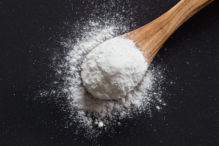 Baking soda on a wooden spoon on dark background, top view, sodium bicarbonate, powder, natural, cooking, baking, 
