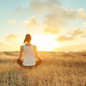 Benefits of meditation - woman meditating in field