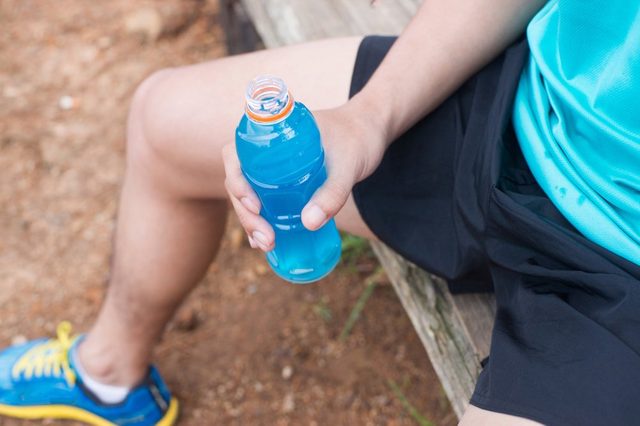 Bottle of energy drink in hands of trail runner.