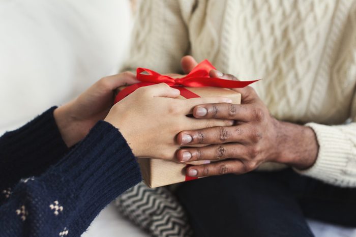 Presenting gifts as Christmas eve tradition. African-american couple exchanging xmas presents, closeup, copy space