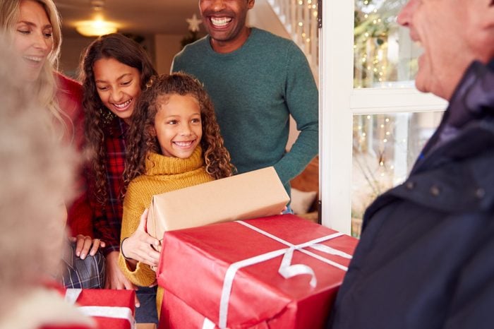 Grandparents Arriving With Gifts To Celebrate Multi-Generation Family Christmas At Home