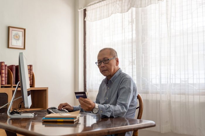 Senior man shopping online using computer and credit card.