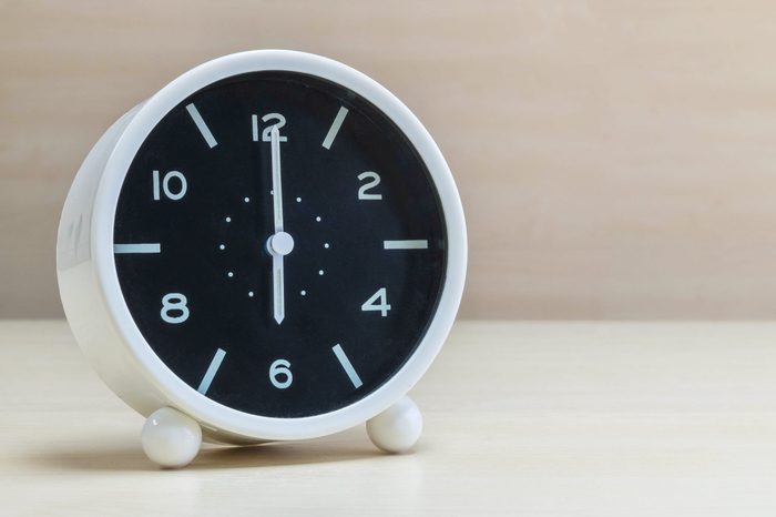 Closeup alarm clock for decorate in 6 o'clock on brown wood desk and wall textured background with copy space