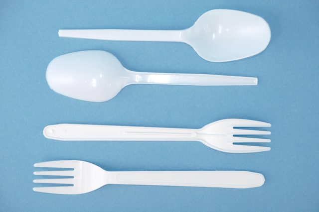 two plastic spoons and two plastic forks on blue background
