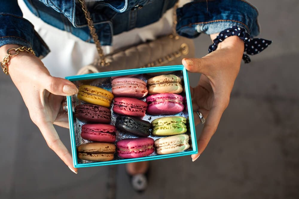 Woman holding box with colourful macaroons. Dessert. Summer travel vacation in French Riviera.