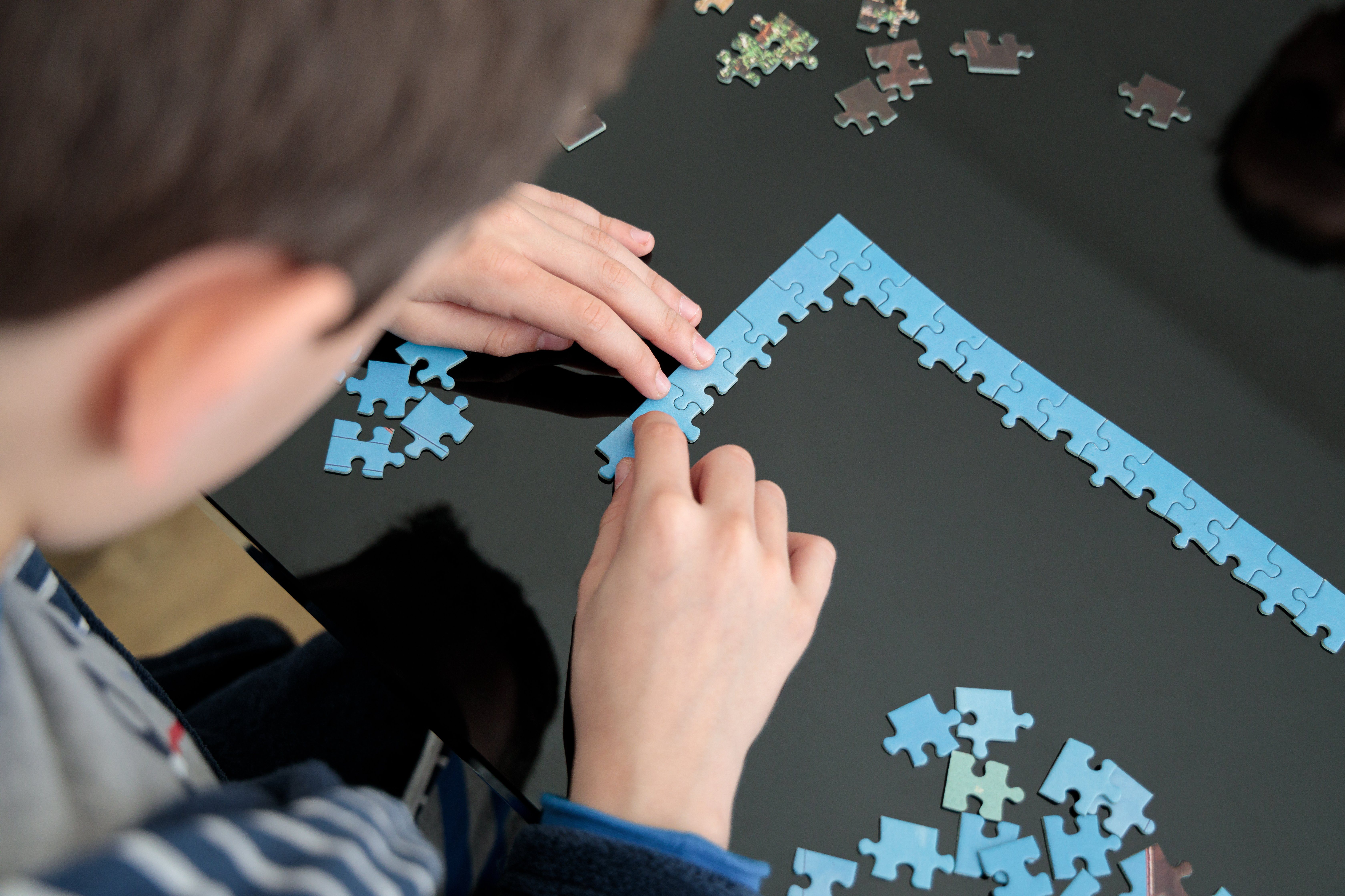 Hands, head and jigsaw puzzle pieces on a table