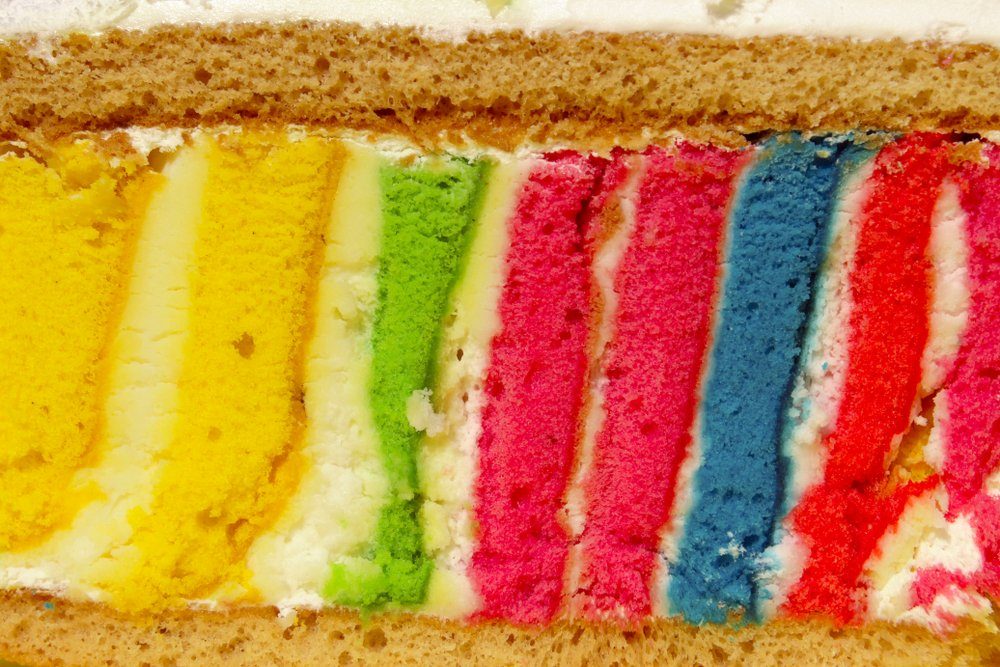 Cropped Shot Of A Slice Of Delicious Colored Cake. Rainbow Cake, Close-Up.Summer Colors.Colorful Dessert Background.