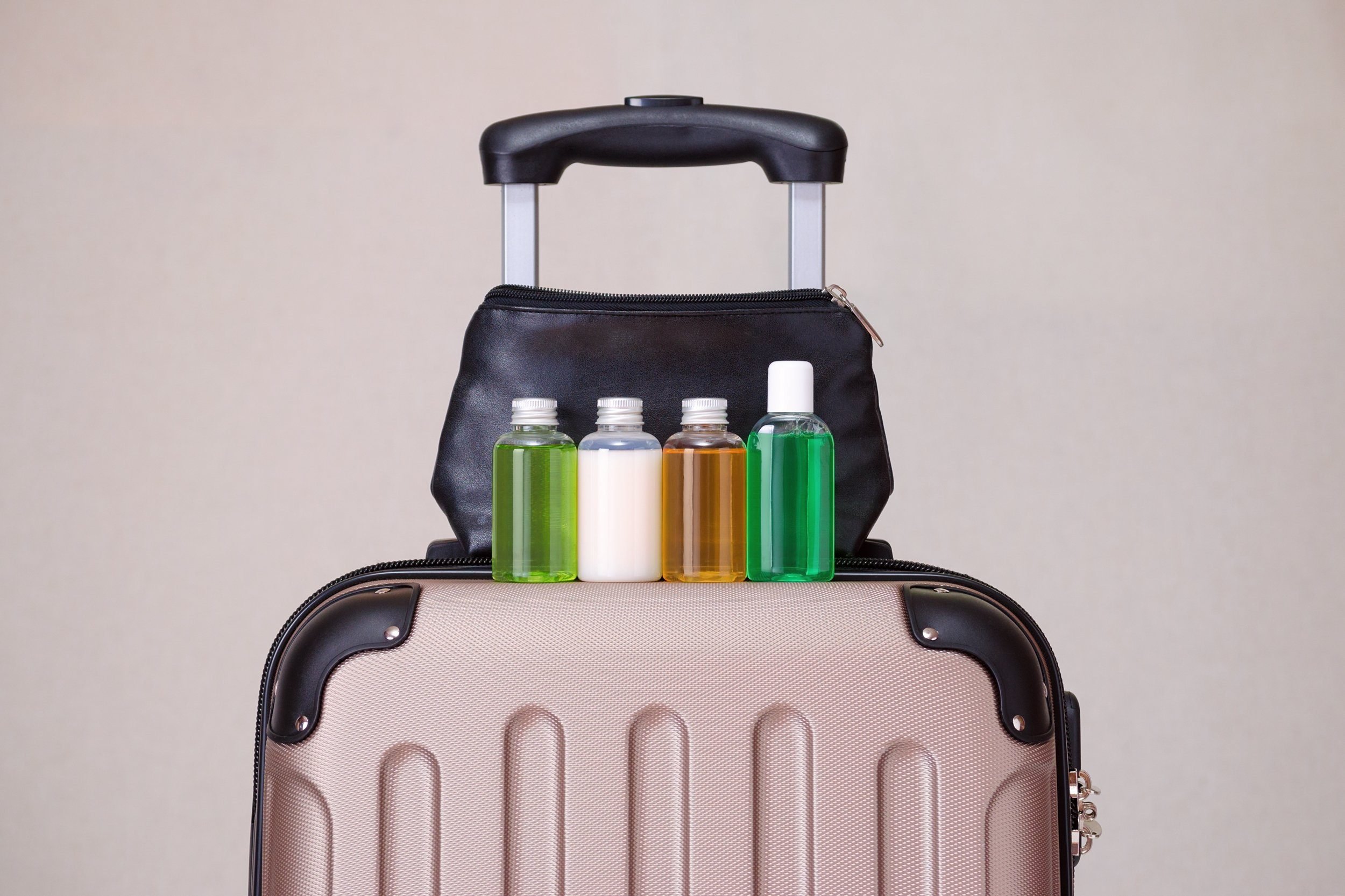 travel toiletries, small plastic bottles of hygiene products on the suitcase and cosmetic bag