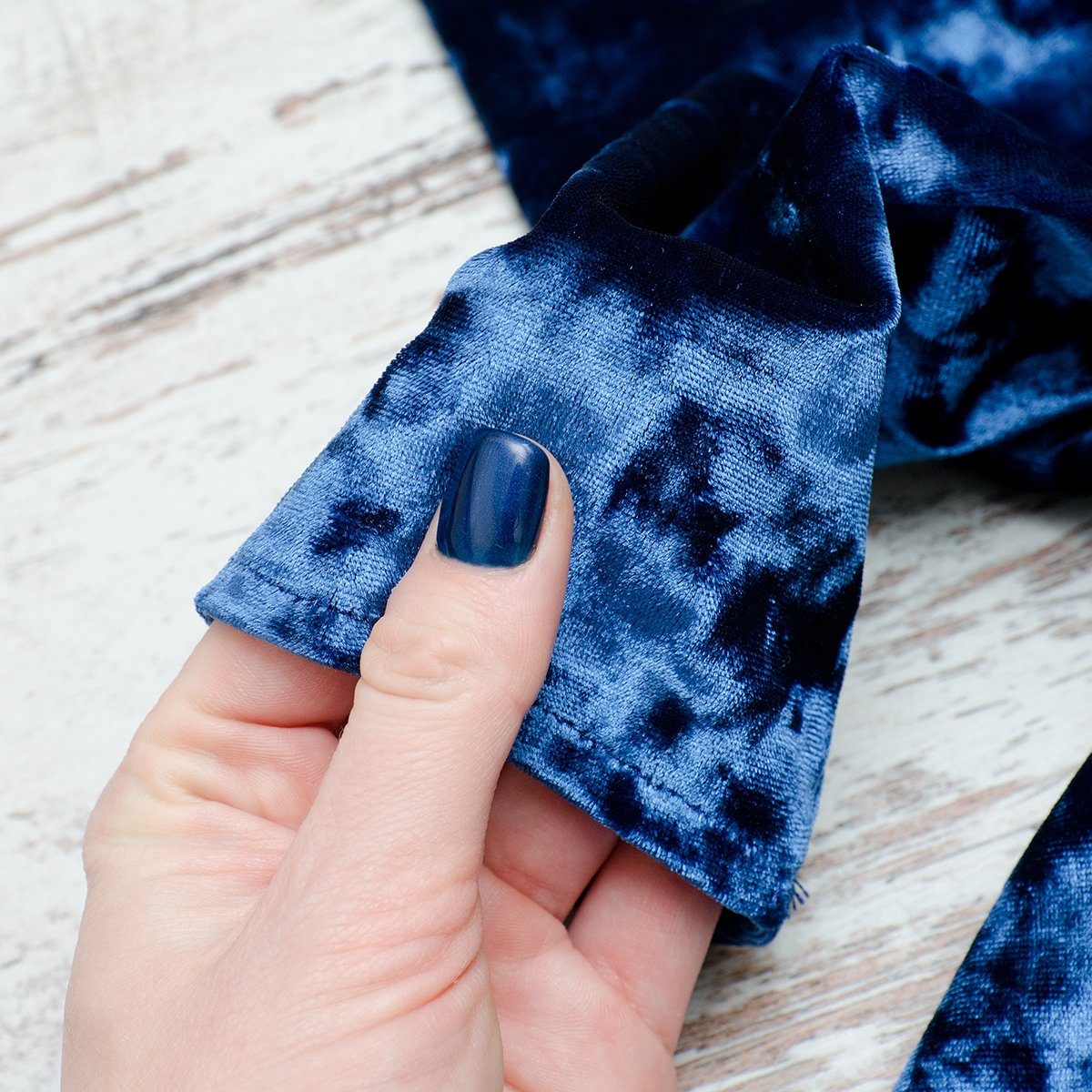 Sleeve of blue velvet dress in female hand. Fashionable concept