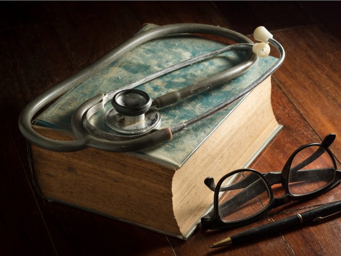 Stethoscope with eyeglasses, pen and antique book