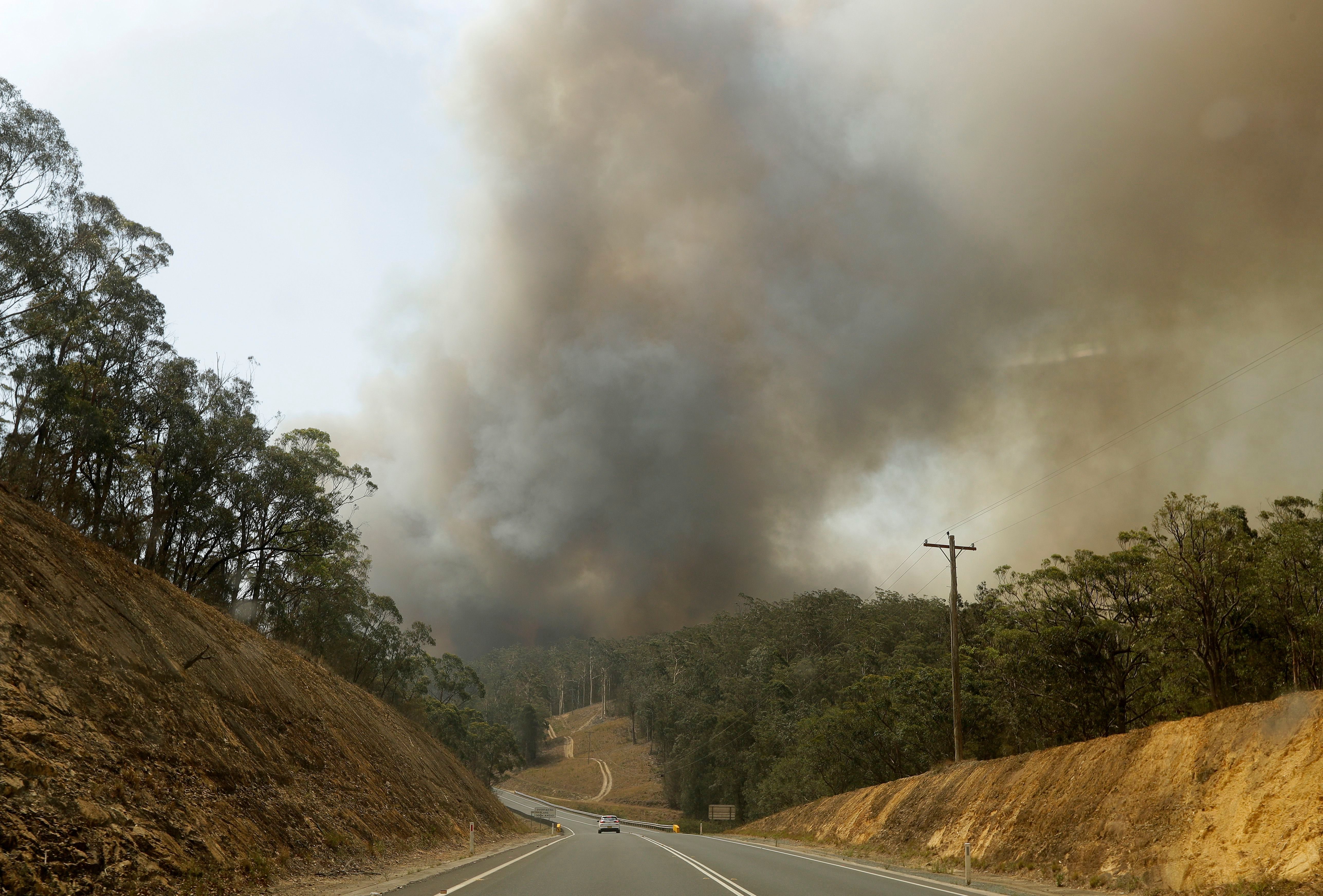 Mandatory Credit: Photo by Rick Rycroft/AP/Shutterstock (10517722c) Smoke from a fire at Batemans Bay, Australia, billows into the air, . Australia's prime minister called up about 3,000 reservists as the threat of wildfires escalated in at least three states on Saturday, while strong winds and high temperatures were forecast to bring flames to populated areas including the suburbs of Sydney Wildfires, Batemans Bay, Australia - 04 Jan 2020