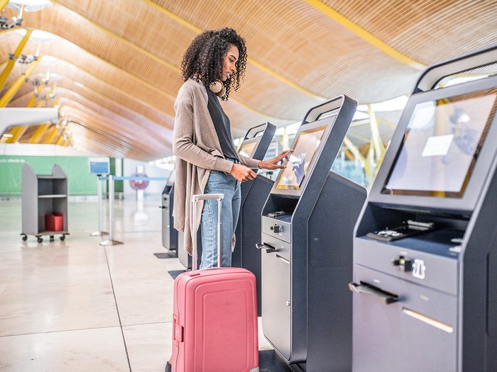 Woman using self check-in terminal at airport