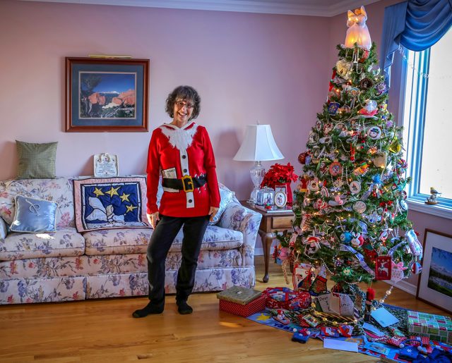 Woman in Santa sweater standing beside her Christmas tree