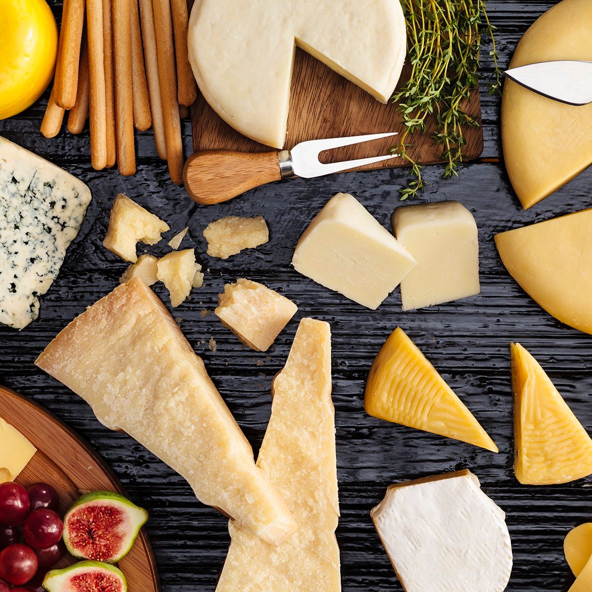 Top view of a dark table filled with a wide variety of cheeses.