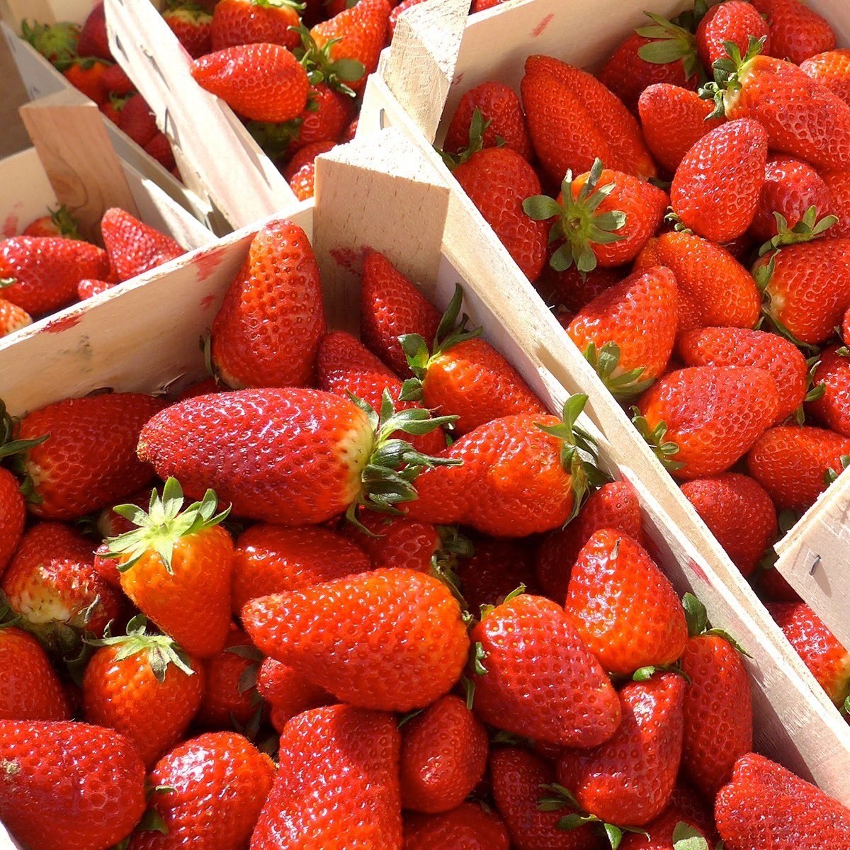 Fresh strawberries in wooden boxes, ready for sale.