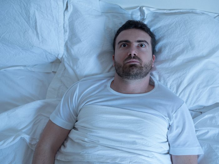 Man lying in bed staring at ceiling